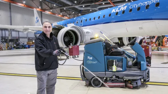 schoonmaker spuit water naast vliegtuig