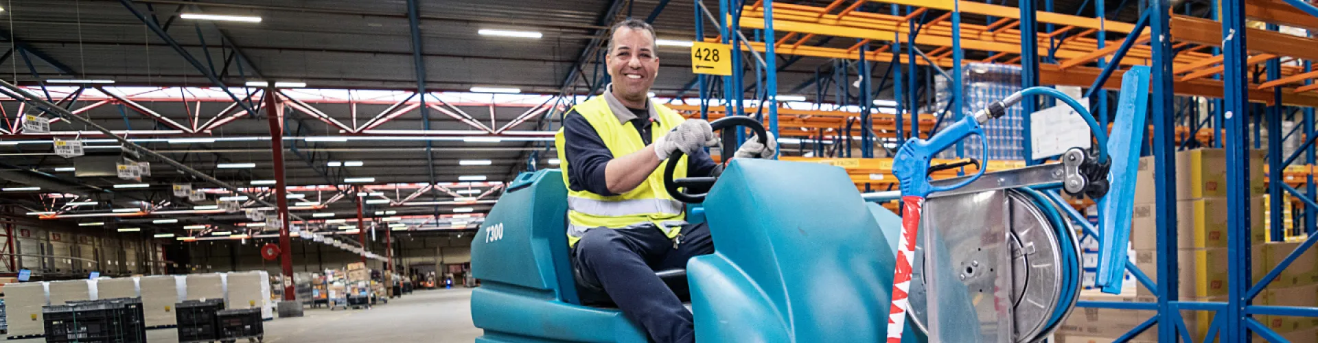 Schoonmaker op machine in logistieke ruimte