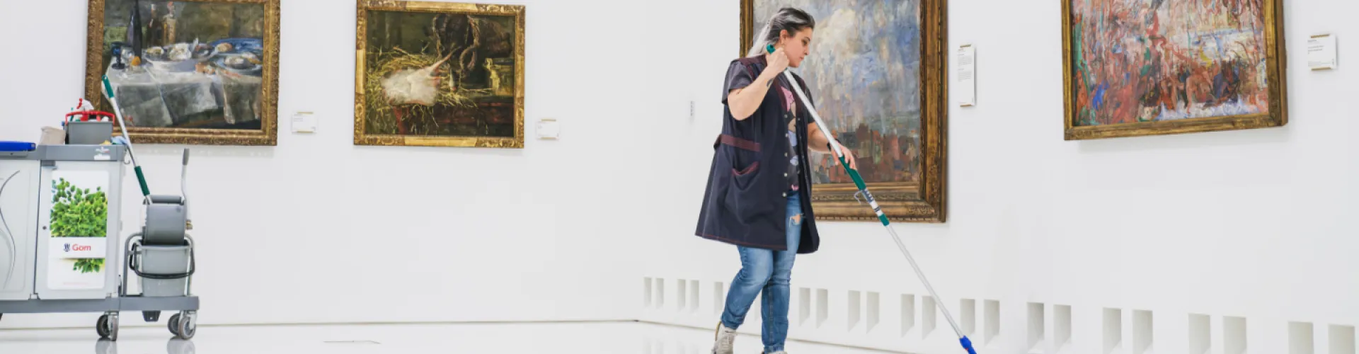 schoonmaakster dweilt witte vloer in museum