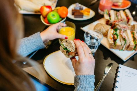 vrouw heeft broodje en glas fruitsap vast